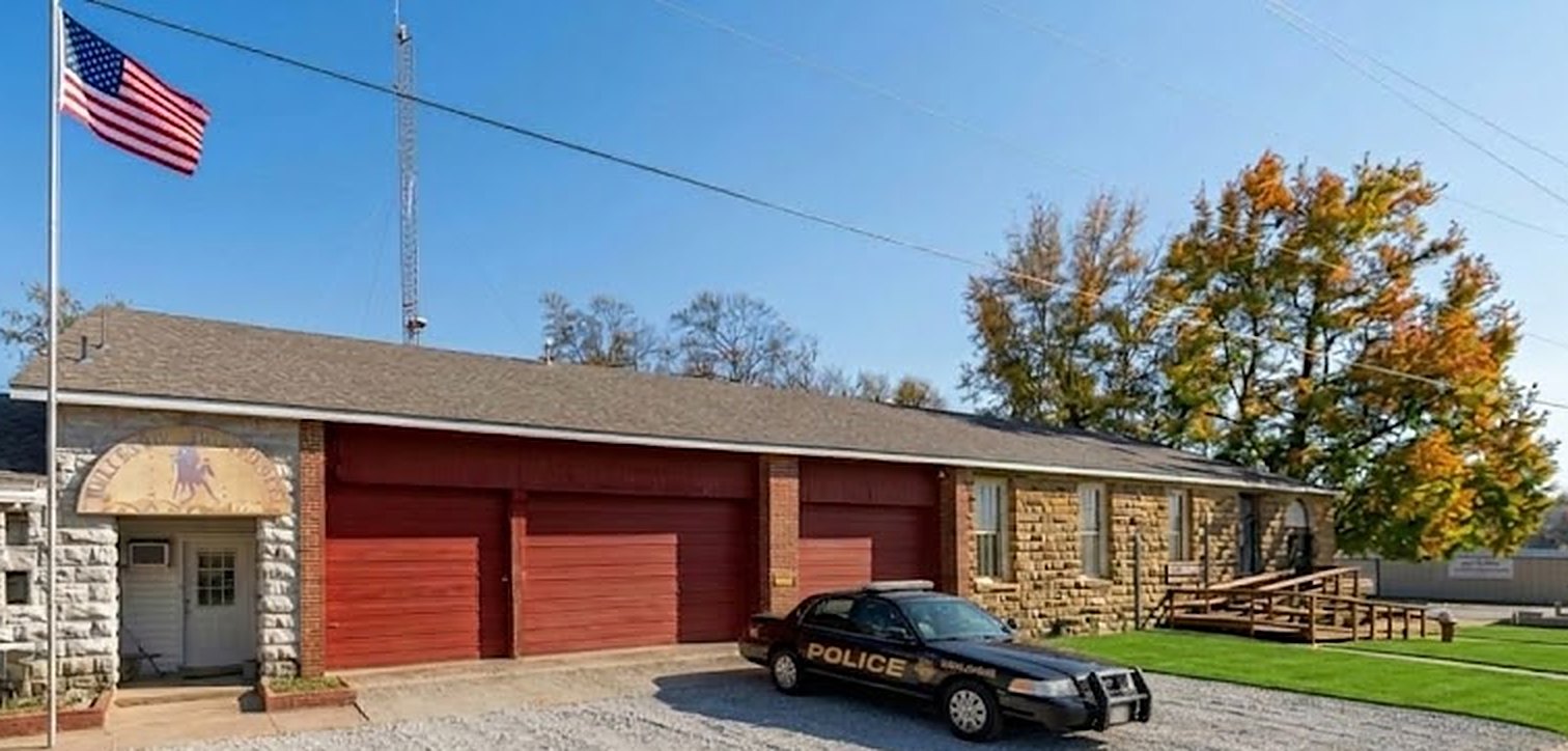 A police patrol car parked in front of a brick and stone building with red garage doors